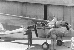 1955 Oct - Mary Carmel under wing as Tom's plane gets serviced in front of hanger in Little Rock, AR